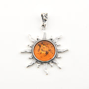 Silver sun-shaped pendant with amber center on a white background