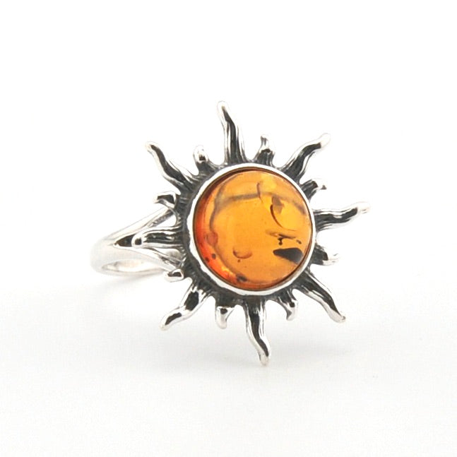 Silver ring with a sun design and amber stone on a white background
