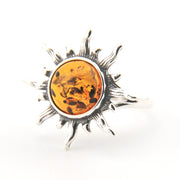 Silver sun-shaped pendant with amber center on a white background