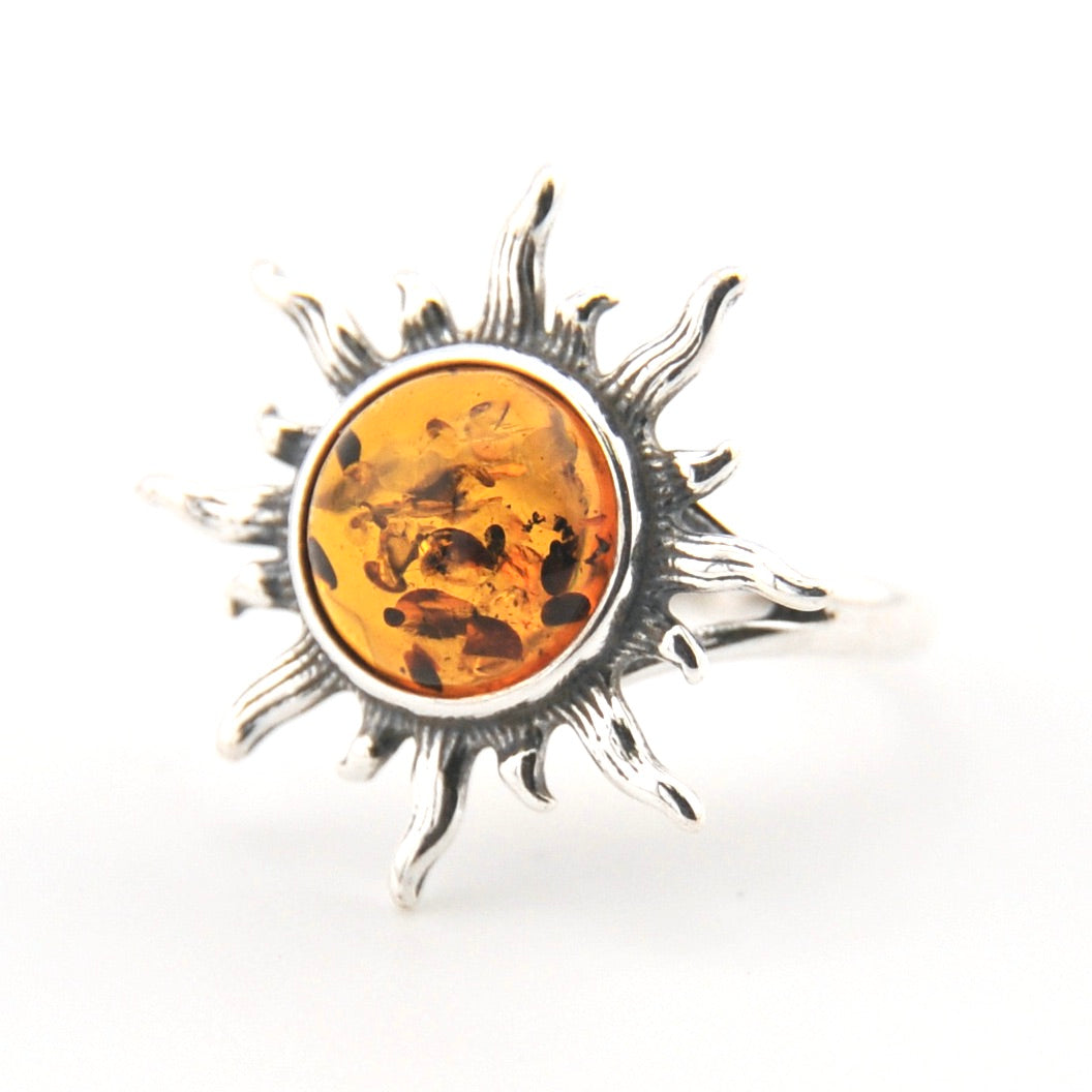 Silver sun-shaped pendant with amber center on a white background