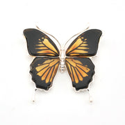 Butterfly-shaped pendant with black and gold wings on a white background