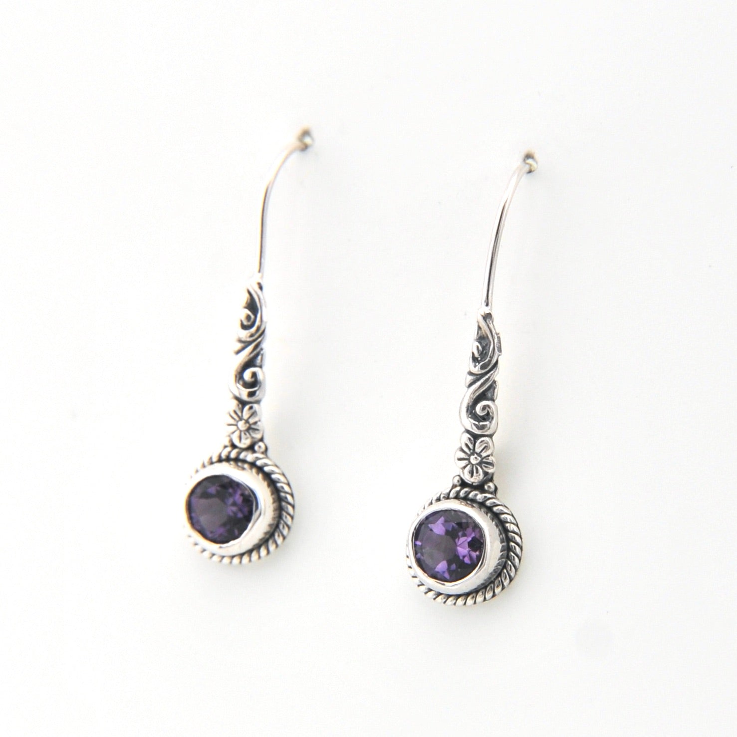 Silver earrings with purple gemstones on a white background