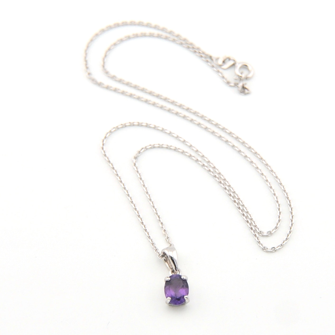 Silver necklace with a purple gemstone pendant on a white background