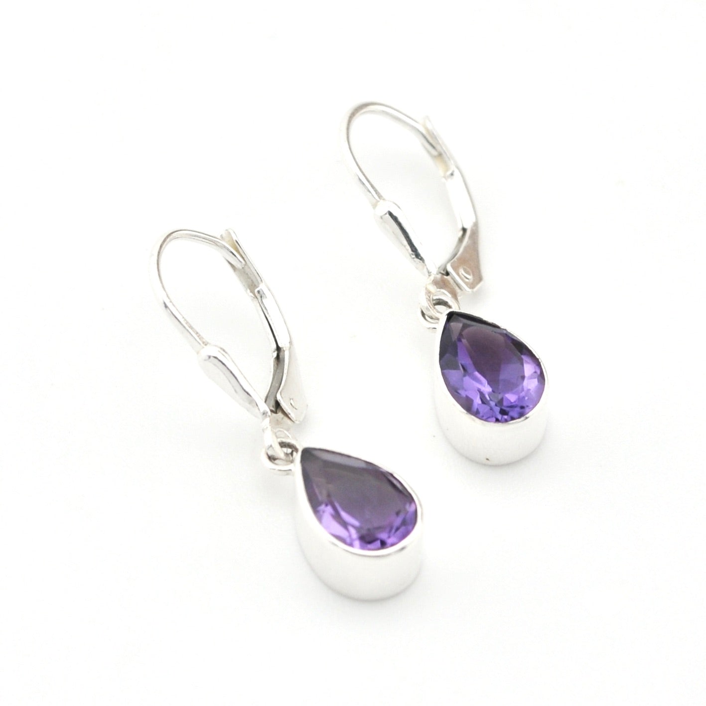 Silver earrings with purple teardrop-shaped gemstones on a white background