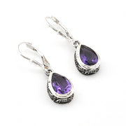 Pair of silver earrings with purple gemstones on a white background