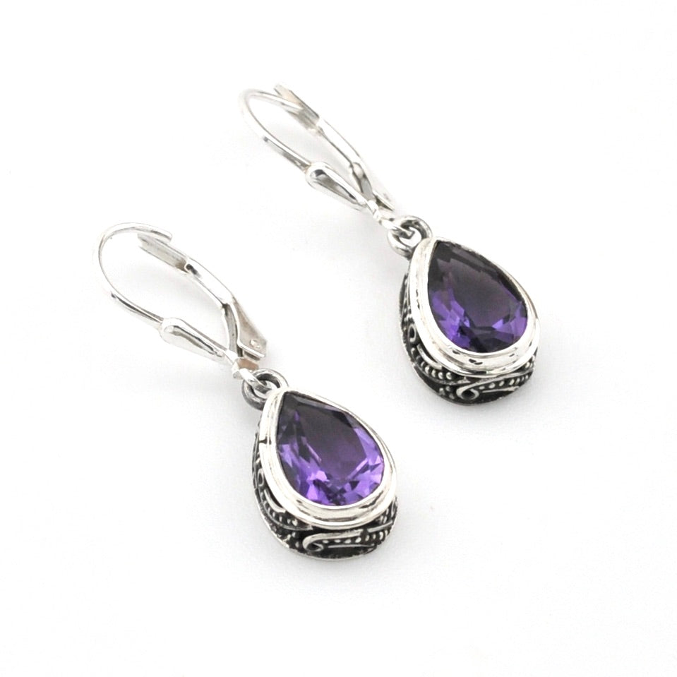 Pair of silver earrings with purple gemstones on a white background