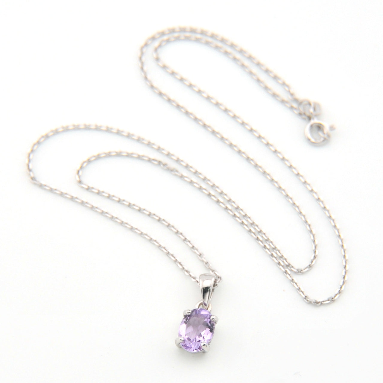 Silver necklace with a purple pendant on a white background