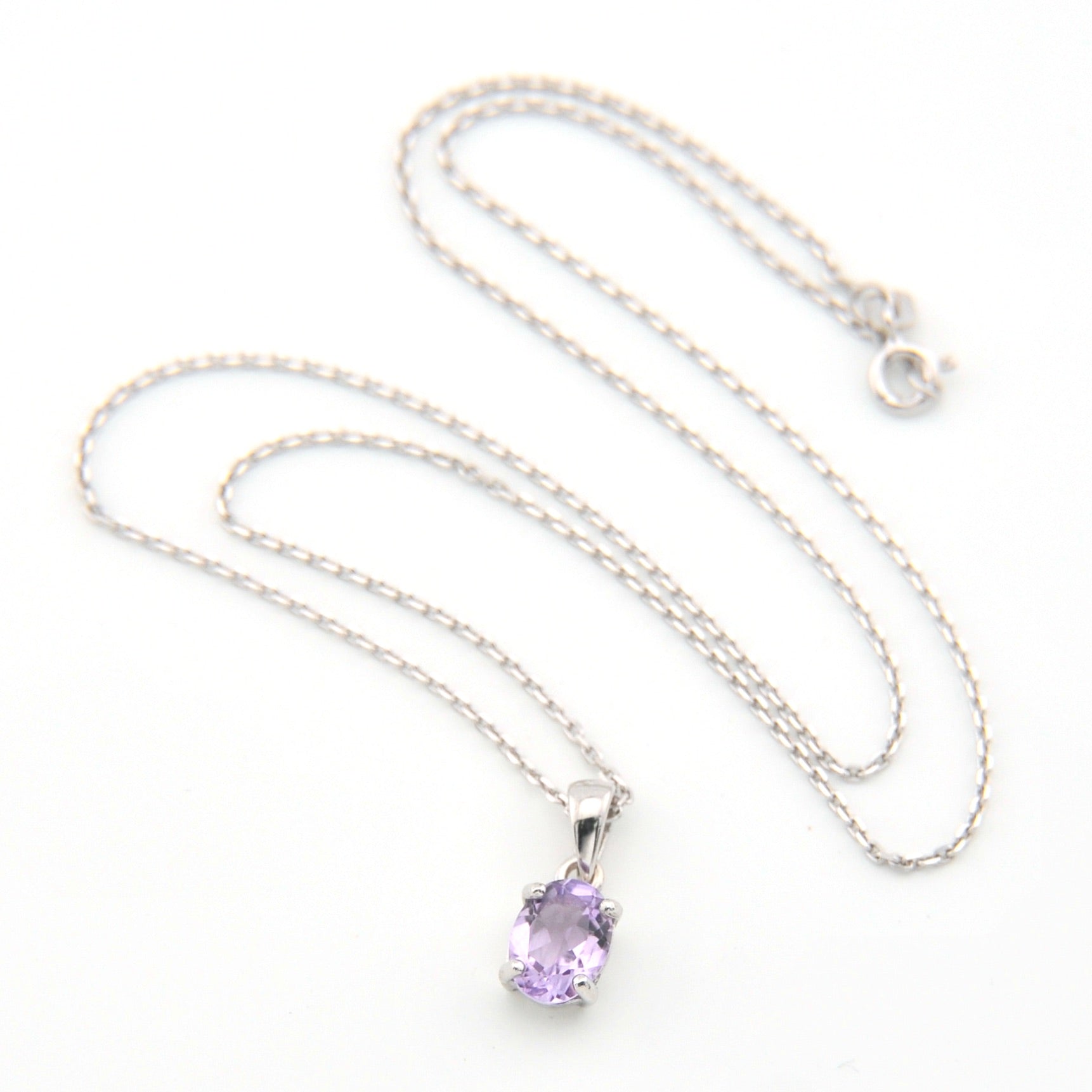 Silver necklace with a purple pendant on a white background