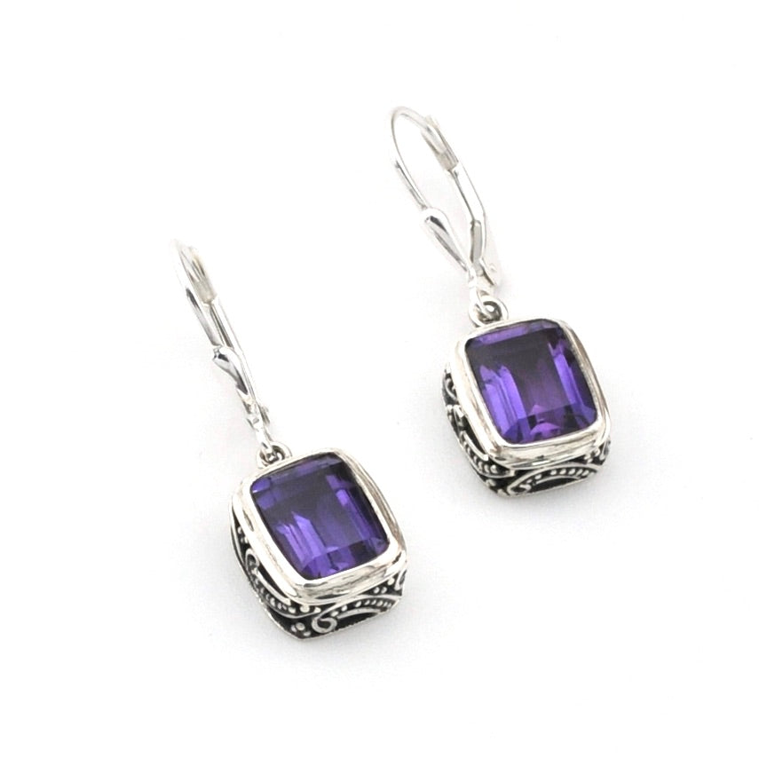 Pair of silver earrings with purple gemstones on a white background