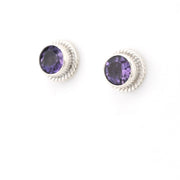 Pair of silver earrings with purple gemstones on a white background