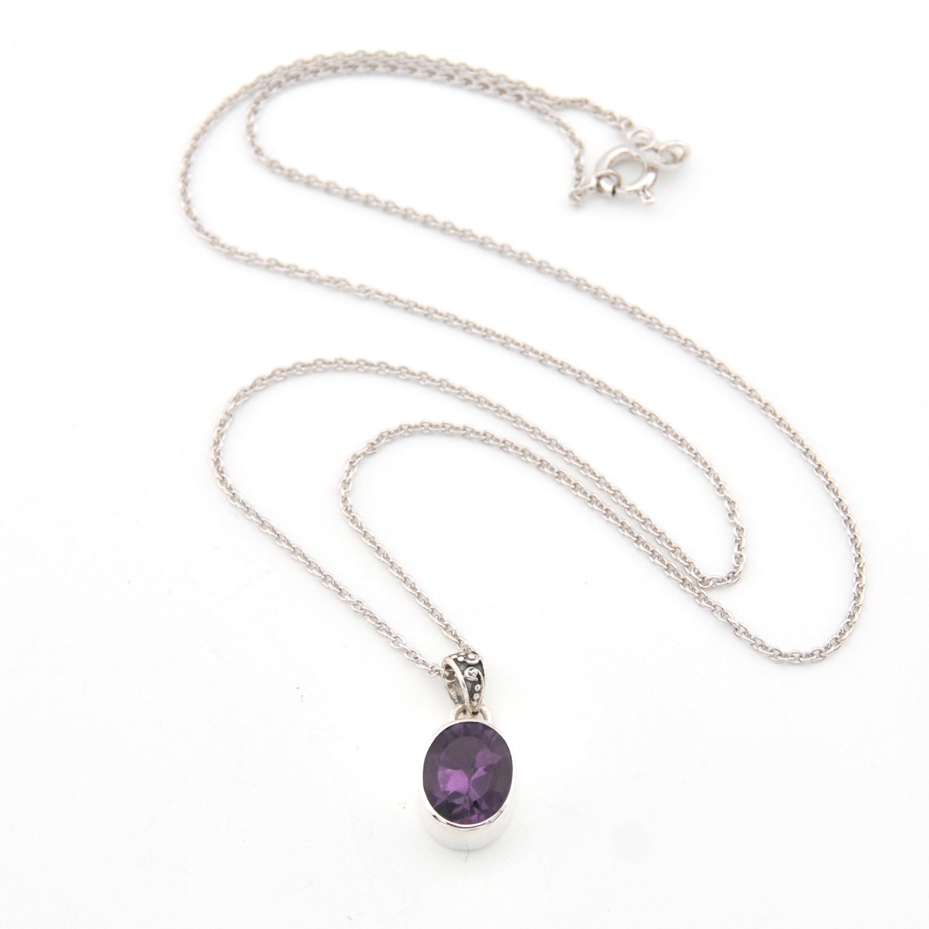 Silver necklace with a purple pendant on a white background