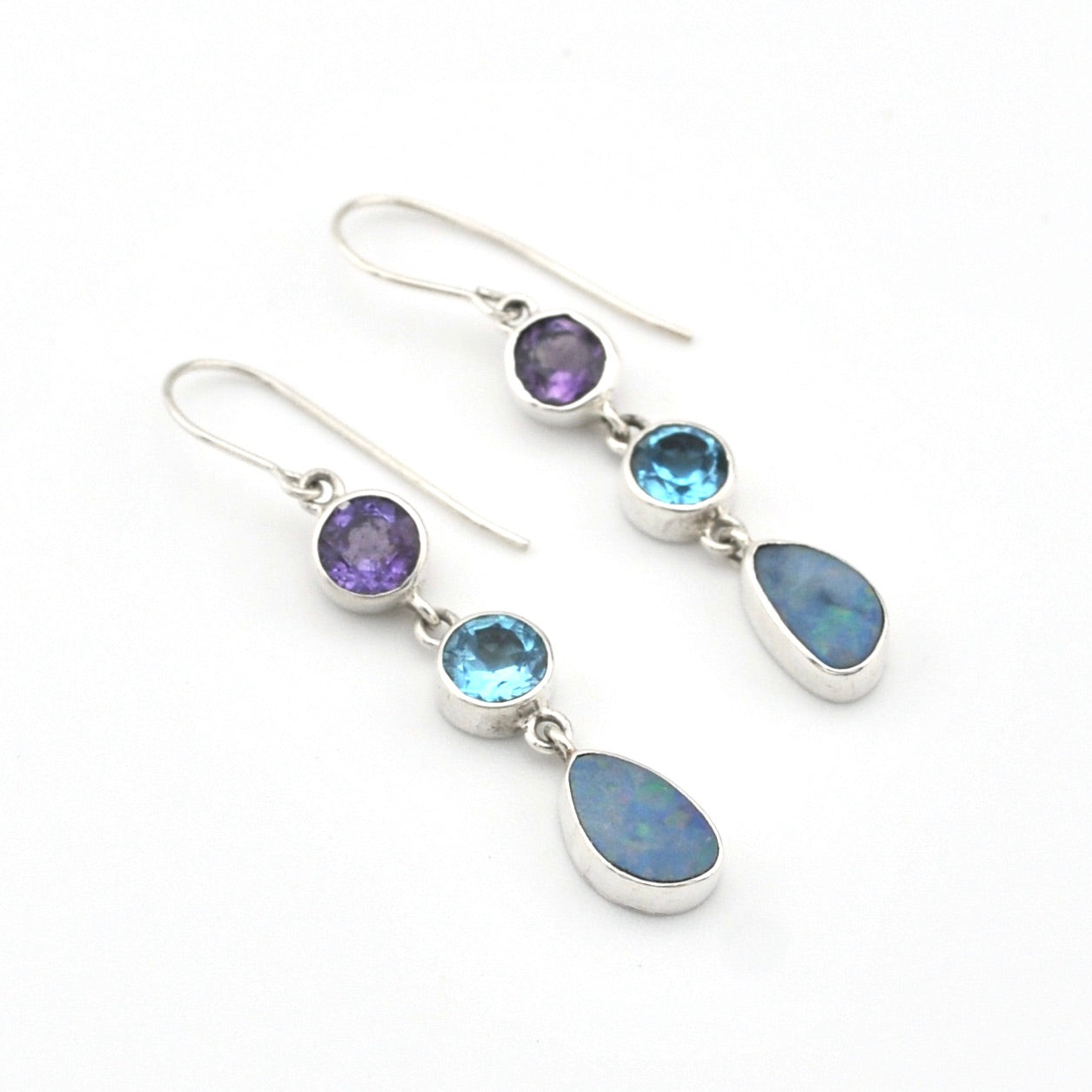 Silver earrings with purple, blue, and clear gemstones on a white background