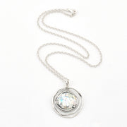 Silver necklace with a round pendant on a white background