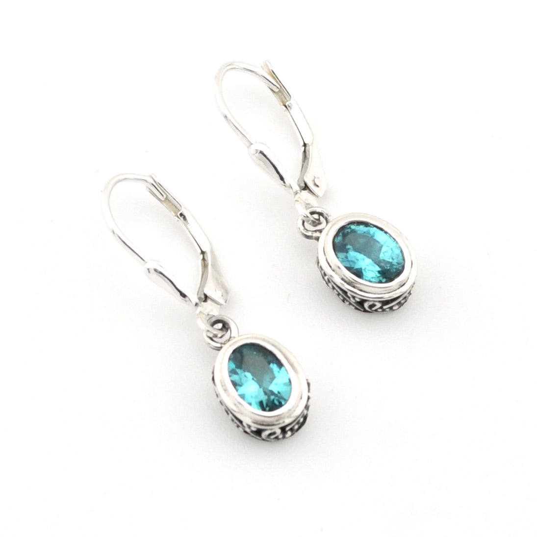 Silver earrings with blue gemstones on a white background