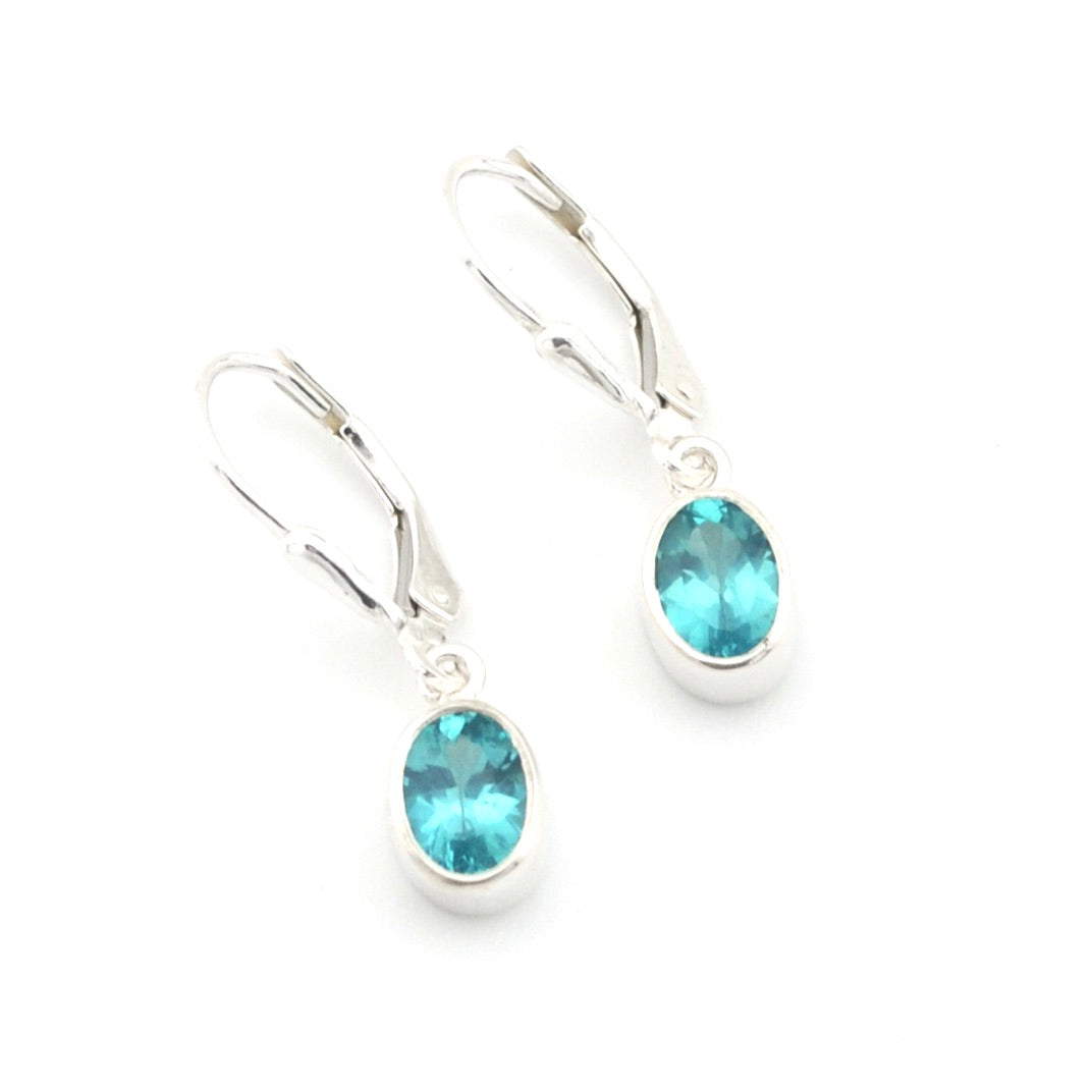 Silver earrings with blue gemstones on a white background