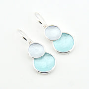 Pair of earrings with light blue circular stones on a white background