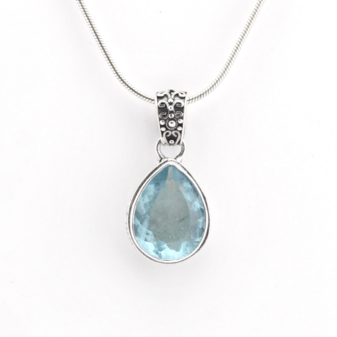 Teardrop-shaped blue gemstone pendant on a white background