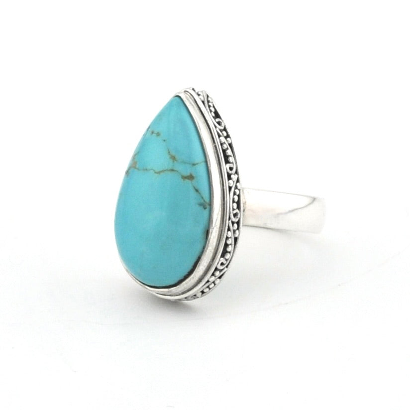 A sterling silver ring featuring a teardrop-shaped turquoise stone with natural matrix lines, set against a clean white background.