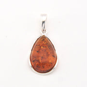 Teardrop-shaped amber pendant on a silver chain against a white background