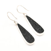 Black teardrop earrings with silver hooks on a white background