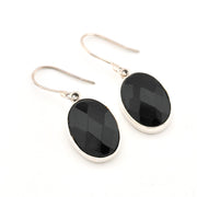 Black oval stone earrings with silver hooks on a white background