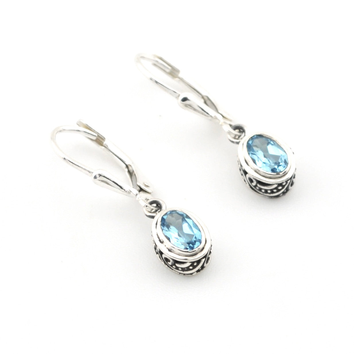 Pair of silver earrings with blue gemstones on a white background