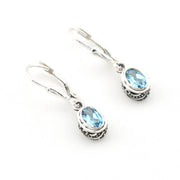 Pair of silver earrings with blue gemstones on a white background