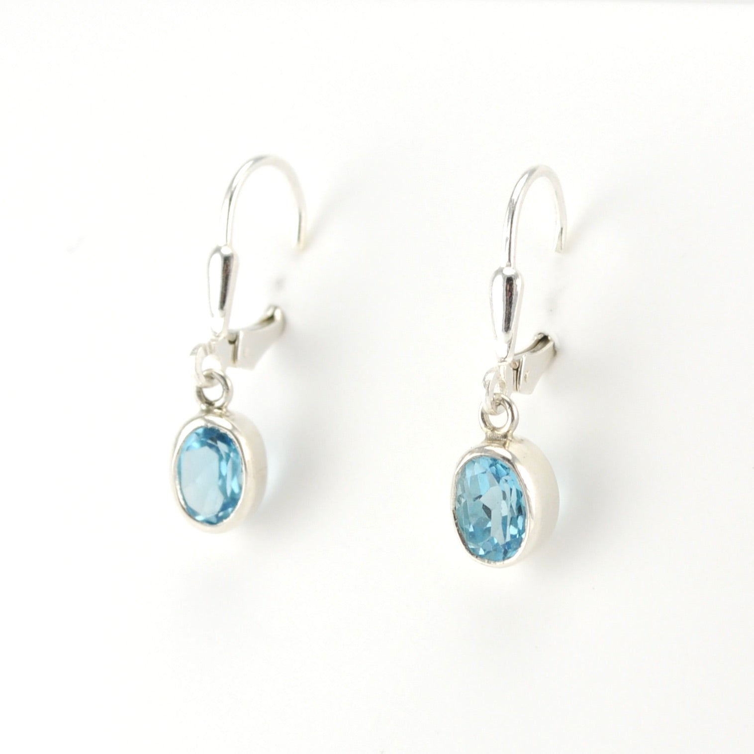 Silver earrings with blue gemstones on a white background
