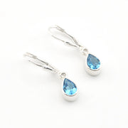 Silver earrings with blue teardrop-shaped gemstones on a white background