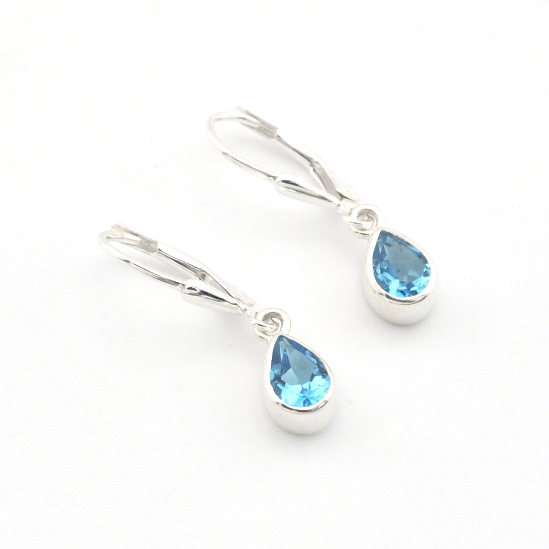 Silver earrings with blue teardrop-shaped gemstones on a white background