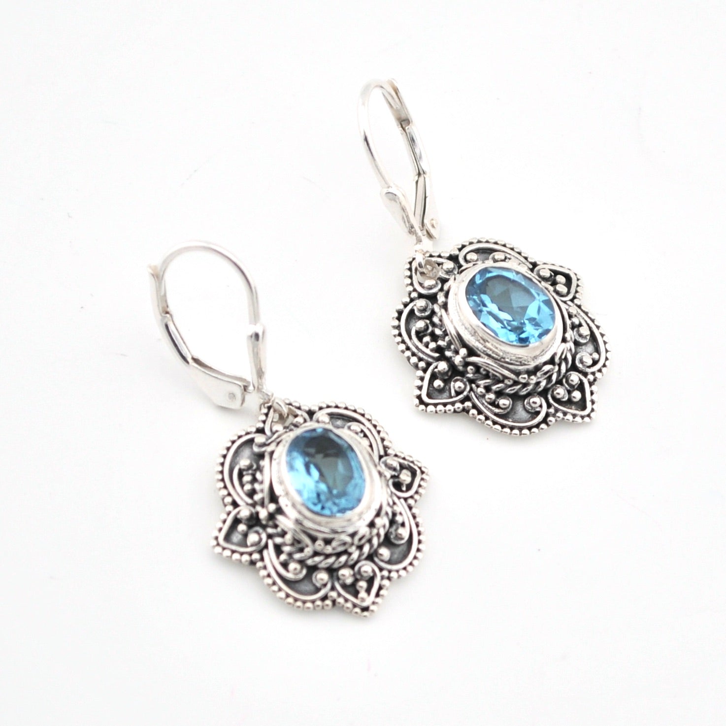 Silver earrings with blue gemstones on a white background