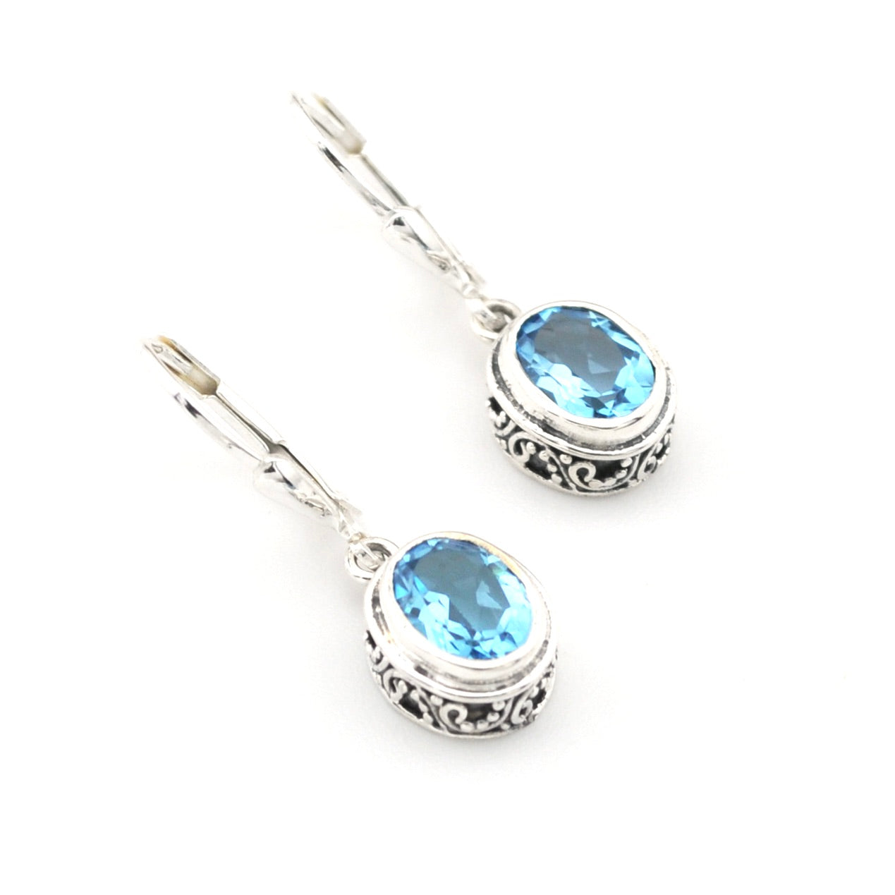 Pair of silver earrings with blue gemstones on a white background