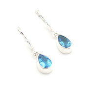 Silver earrings with blue teardrop-shaped gemstones on a white background
