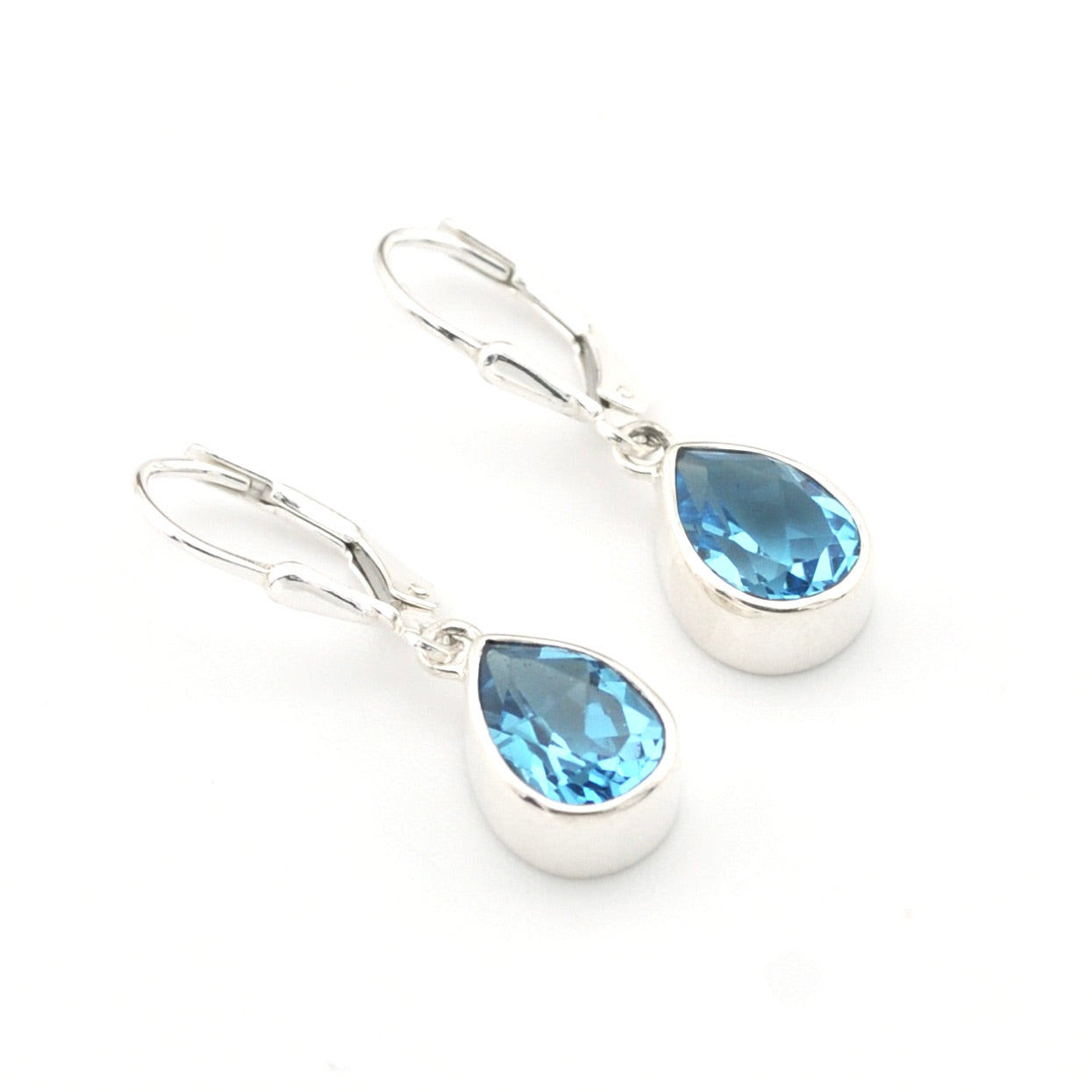 Silver earrings with blue teardrop-shaped gemstones on a white background