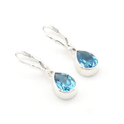 Silver earrings with blue teardrop-shaped gemstones on a white background