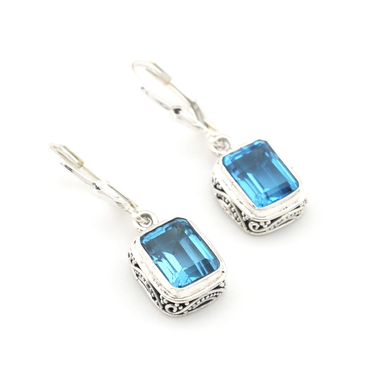 Silver earrings with blue gemstones on a white background