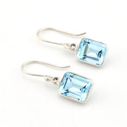 Pair of silver earrings with blue gemstones on a white background