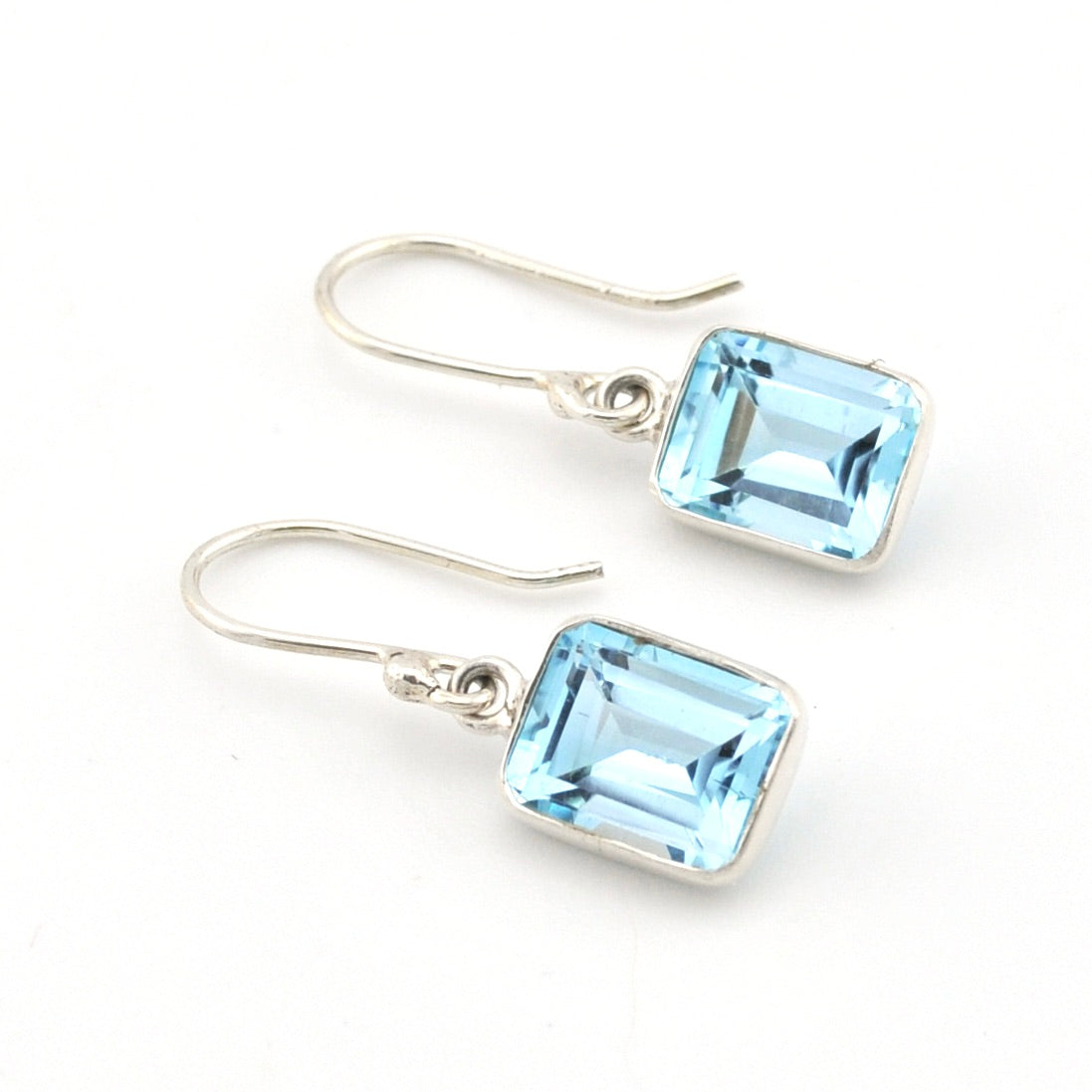 Pair of silver earrings with blue gemstones on a white background