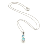 A silver necklace featuring a pendant with a small round light blue gemstone and an oval iridescent opal stone, displayed on a clean white background.