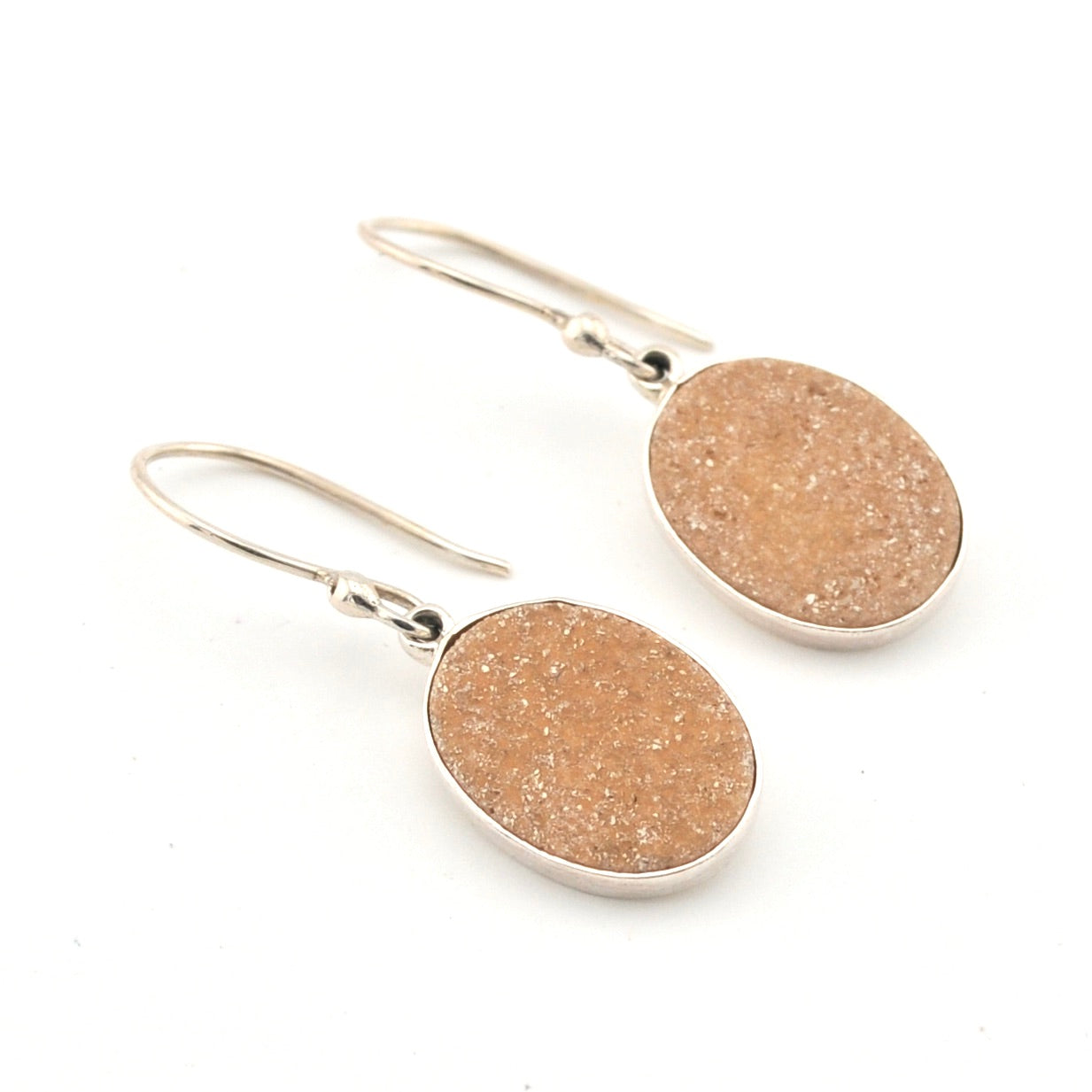 Pair of earrings with beige round stones on a white background
