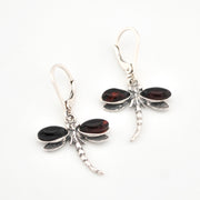 Dragonfly-shaped earrings with cherry amber and silver design on a white background