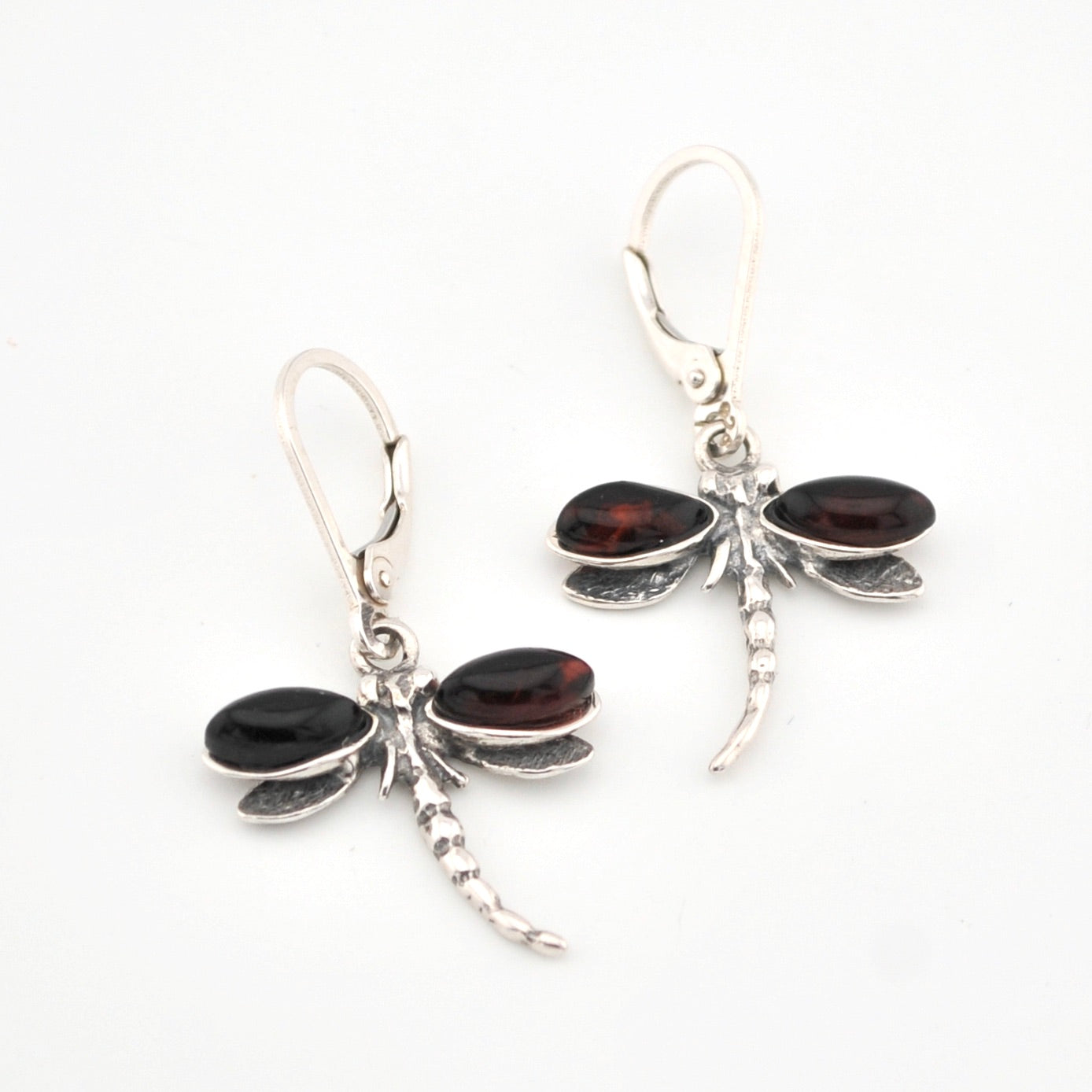 Dragonfly-shaped earrings with cherry amber and silver design on a white background