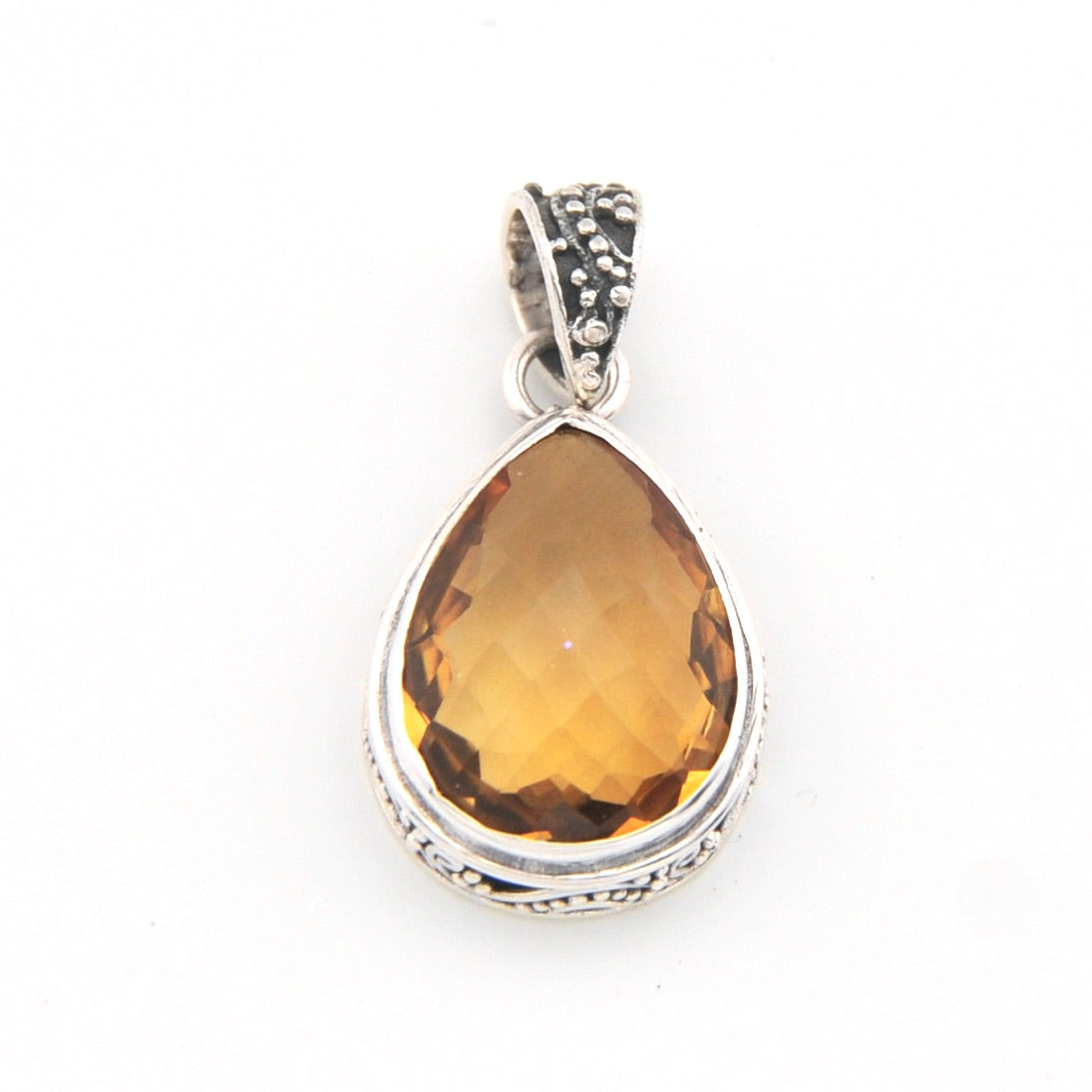 Teardrop-shaped citrine pendant with silver setting on a white background