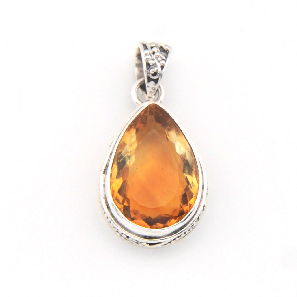 Teardrop-shaped citrine pendant on a white background