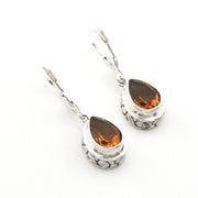 A pair of silver leverback drop earrings featuring teardrop-shaped orange gemstones in a textured silver bezel setting, shown on a plain white background.