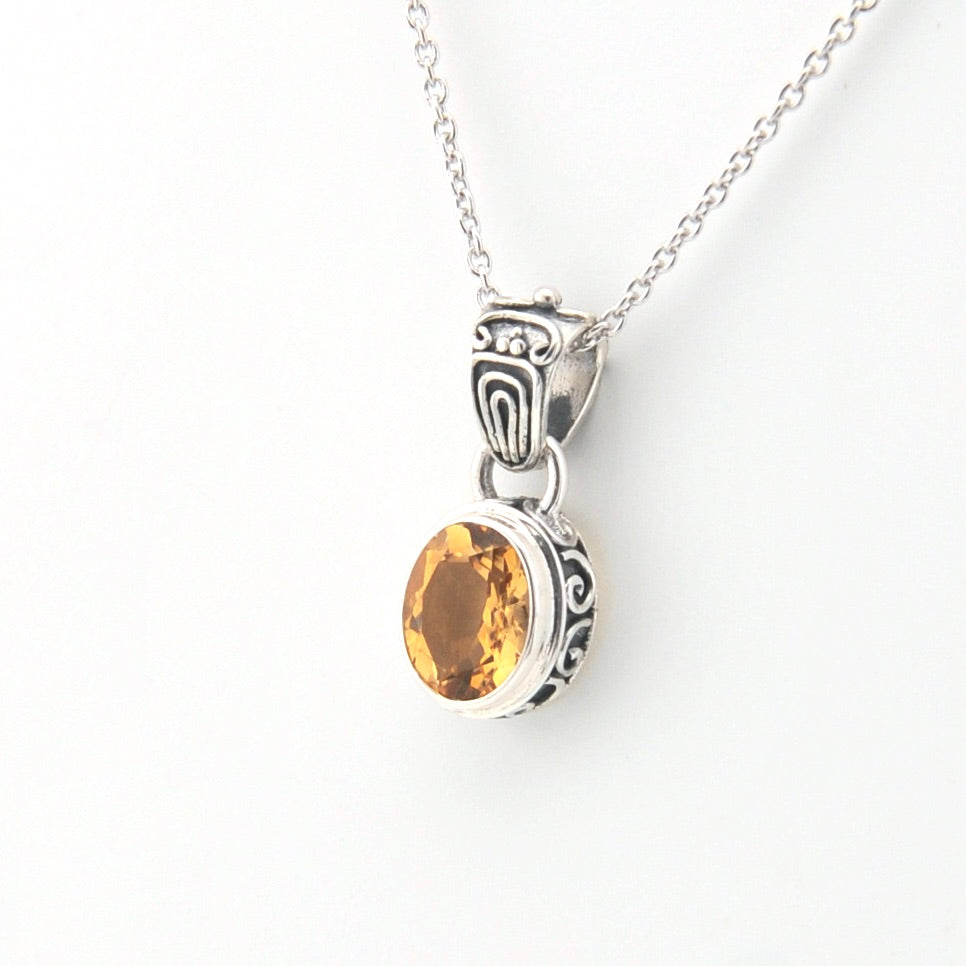 Silver pendant with a yellow gemstone on a white background