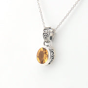 Silver pendant with a yellow gemstone on a white background