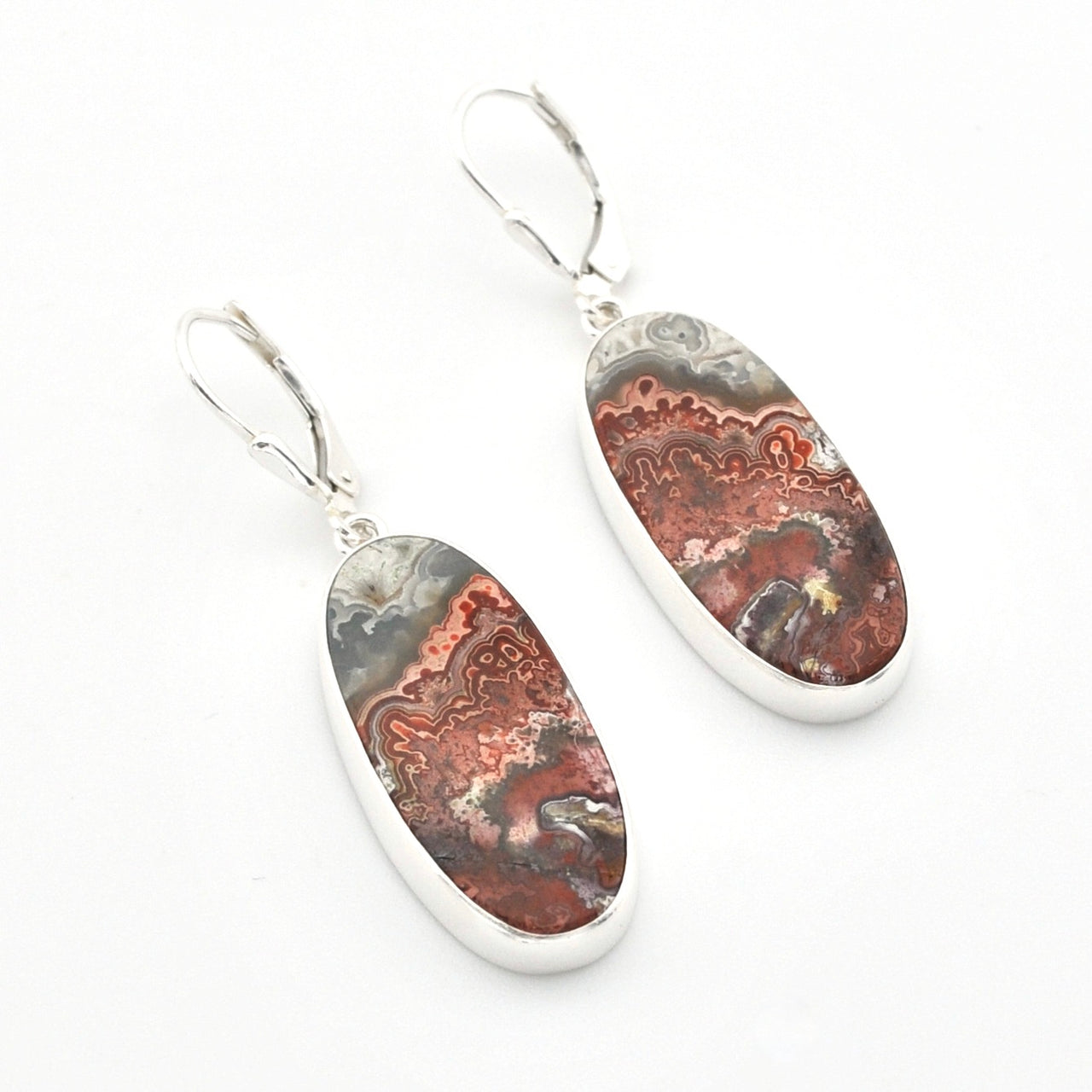 A pair of silver leverback earrings with oval dangle charms featuring a polished agate or jasper stone pattern in earthy brown, rust, gray, and cream tones, set against a plain white background.