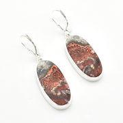 A pair of silver leverback earrings with oval dangle charms featuring a polished agate or jasper stone pattern in earthy brown, rust, gray, and cream tones, set against a plain white background.