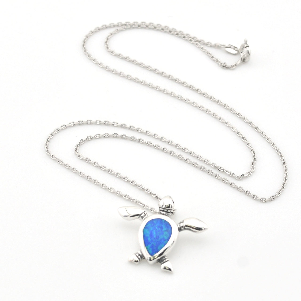 Silver turtle pendant with blue stone on a chain against a white background